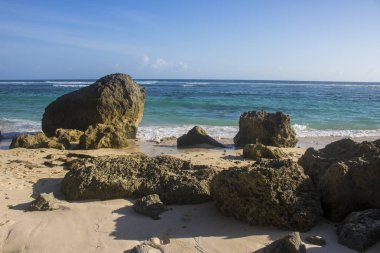 deniz ve mavi gökyüzü ile kumlu plajda kayalar güneş ışıklı