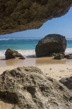 deniz ve mavi gökyüzü ile kumlu plajda kayalar güneş ışıklı