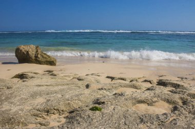 deniz ve mavi gökyüzü ile kumlu plajda kayalar güneş ışıklı