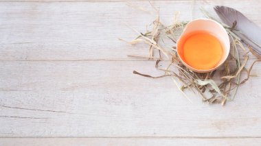 Beyaz ahşap arka planda saman üzerinde sarısı olan organik yumurta. Sağlıklı yiyecekler.