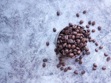 Gri arka planda paslı bir teneke kutuda kavrulmuş kahve çekirdekleri. Metnin için fotokopi alanı var. Üst görünüm