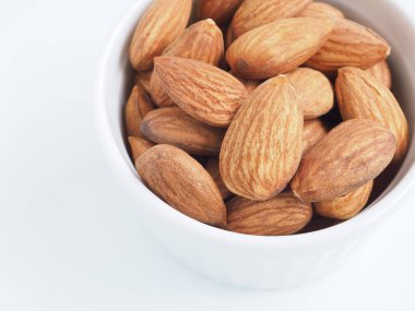 Badem tohumlarını beyaz arka planda izole edilmiş beyaz bir kaseye koy..