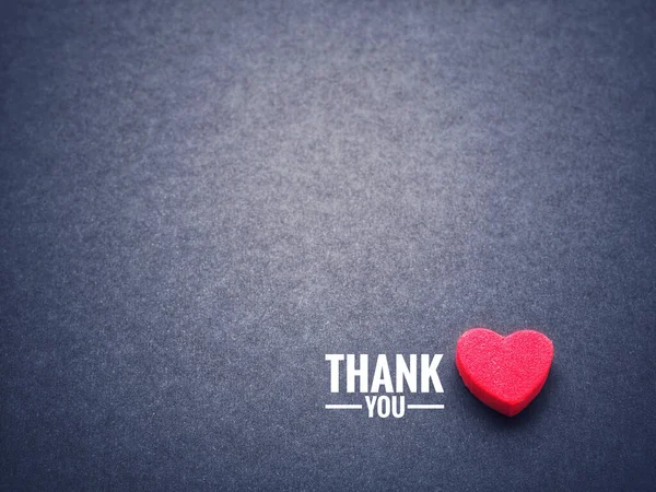 The words thank you and the red heart on the black paper background