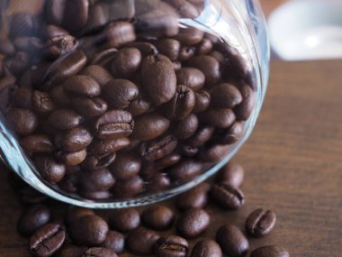 Ahşap arka planda cam şişede kavrulmuş kahve çekirdekleri..  