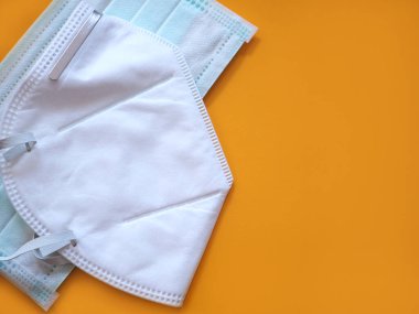 Sarı arka planda koruyucu ve tıbbi yüz maskesi. Kopyalama alanı olan üst görünüm. Sağlık ve Tıp Konsepti