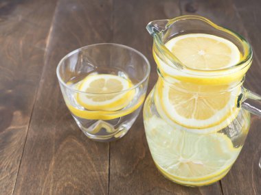 Su ve limonlar kavanoza ve tahta zemine cam dilimler, detoks için içerler ve vücudu tazelerler.
