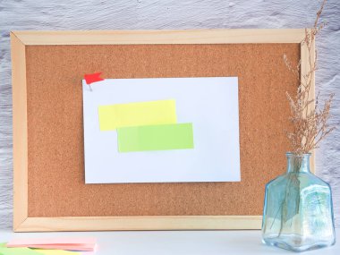 Beyaz arka plandaki vazoda kurutulmuş Caspia ile mantar tahtasına yapıştırılmış post-it notu.