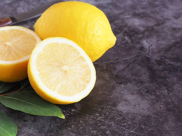 Yapraklı taze limonun yarısı. Gri arka plan ve fotokopi alanı. Yüksek C vitamini, ağırlığı kontrol eder ve kanser riskini azaltır..