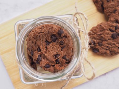 Ev yapımı çift katlı çikolatalı kurabiyeler. Cam şişede, tahta tabakta.