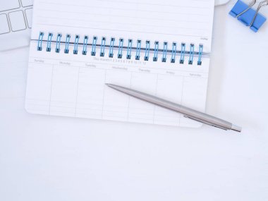 Aylık not defteri ve kalemi olan beyaz çalışma masası. Metin için kopya alanı olan üst görünüm, İş Eğitimi kavramı
