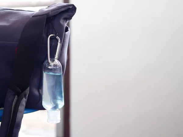 ハンギングイヤー付きボトルで手掃除のためのアルコールジェル 椅子に置かれた灰色の作業袋 細菌やコロナウイルスから防ぐために家を出るたびにそれを取ります ヘルスケアと新しい通常の概念 — ストック写真