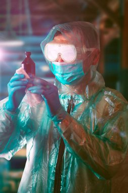 Koruyucu giysili bir doktor ilacı inceliyor..