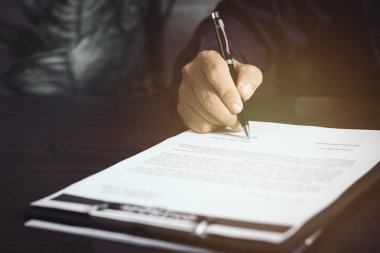 İş adamı ya da avukat masadaki sözleşme kağıdına sigorta ve müdür olarak imza atıyor.