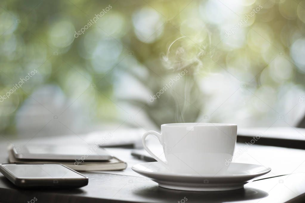 hot cup of coffee on working table with green bokeh background