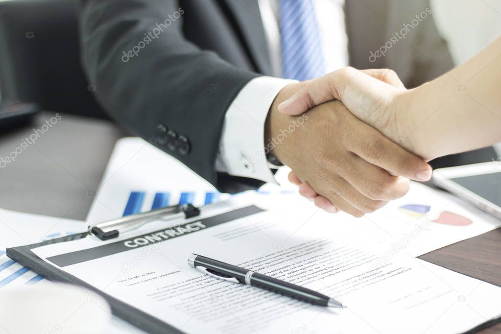 Two businessmen shaking hand after successful negotiate and signing on contract about working and partner together on working table in office.