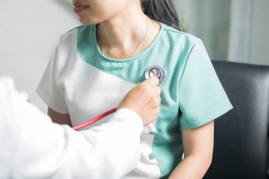 Doktor, kadınların kalbini kontrol etmek için steteskop kullanıyor, hastanede sağlıklı ve güçlü bir konsept. 