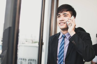 Ofiste telefonda konuşan Genç Asyalı adam.