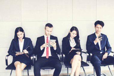 Bir grup iş adamı telefonu boş zaman olarak kullanır ve iş görüşmesi için bekler. 