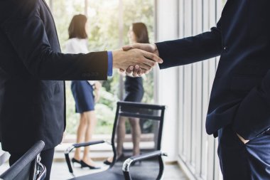 Başarılı bir müzakere ya da ortaklık şirketi, iş adamları toplantı odasında tokalaşıyor