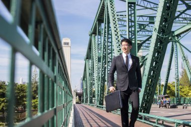 Taylandlı, Asyalı akıllı işadamı, işine güvenle yürüyor, işletme müdürü portresi tutuyor rahatlama ve bacak egzersizi ile seyahat ediyor.