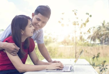 Aşk çifti konuşuyor ve bilgisayarda çalışıyor, karı koca gülüyor ve sabahları dizüstü bilgisayar kullanıyor. 