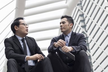 iş insanları merdiven üzerinde konuşmak ve tartışmak için oturuyor