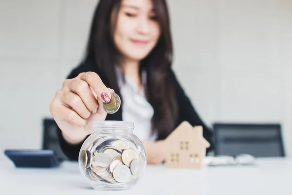 Banker introduces cheap interest for buying residence concept, business woman saving money in glass of jar to get home, housing loan.