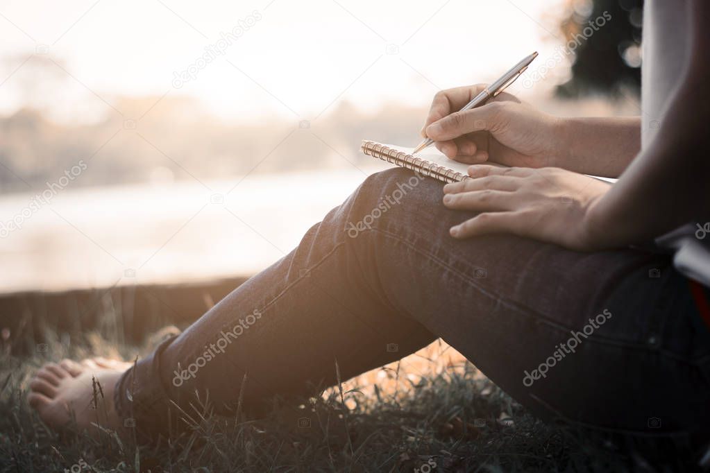 women siting and writing memory on notebook in park in summer