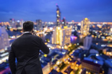 gece şehir arka plan ile kule üstünde işadamı arama telefon