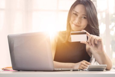 Laptop önünde kredi kartı gösteren kadın, alışveriş online kavramı