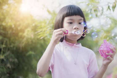 eğlenceli Asyalı çocuk parkta kabarcıklar üfleme