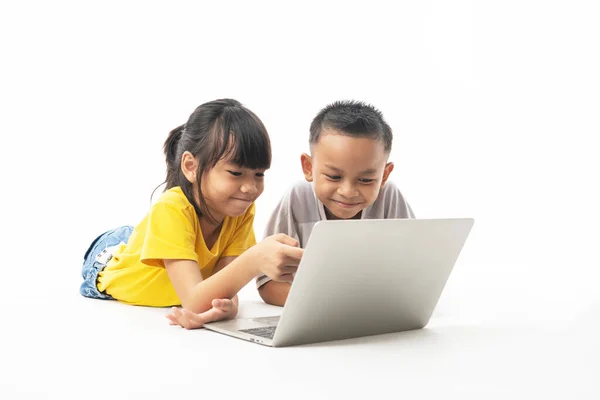 young Asian Thai  kids, boy and girl laying and looking on lapto