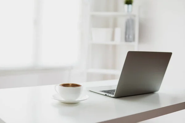 Sala de oficina blanca y clara con ordenador portátil y café en la mesa — Foto de Stock