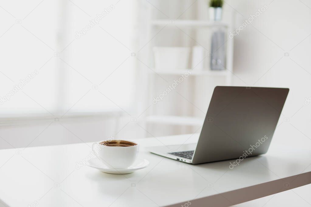 white and clear office room with laptop and coffee on table 