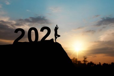 2021 yılının mutlu silueti ve yoga yapan bir kadın.