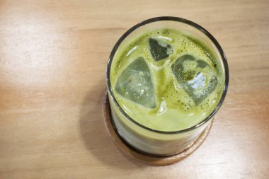 Buz matcha latte ahşap bir masa üzerinde.