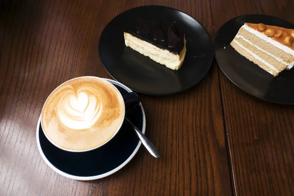 暗い木製のテーブルにケーキとコーヒーのカフェラテ — ストック写真