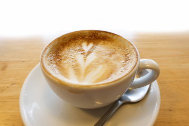 Ahşap bir masa üzerinde sıcak kahve sanatı.