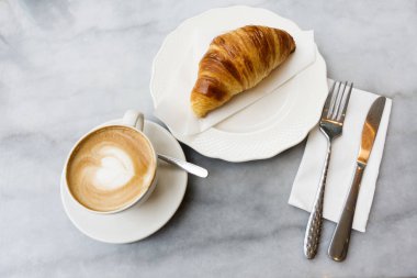 Sıcak kahve ve kruvasan mermer bir tablo.