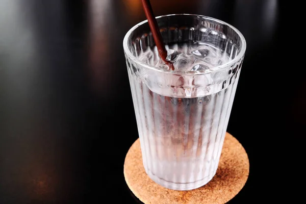 在黑色桌子上的杯子里喝水 — 图库照片