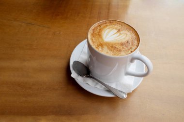 Ahşap bir masa üzerinde sıcak latte