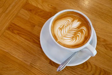 Ahşap bir masa üzerinde sanat Latte Kupası