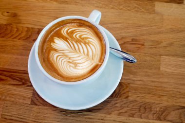 Ahşap bir masa üzerinde sanat Latte Kupası