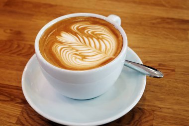 Ahşap bir masa üzerinde sanat Latte Kupası