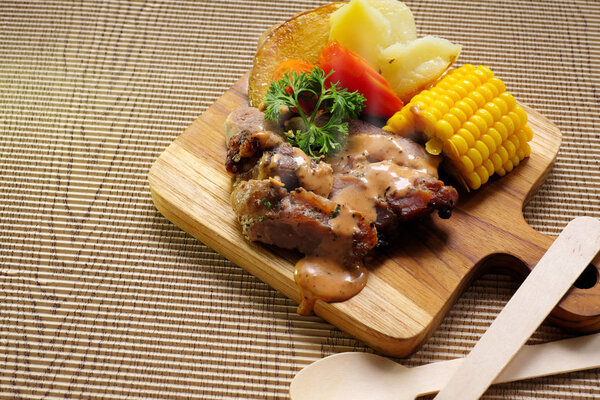 Pork steak with vegetables on wooden board