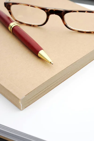 Notebook and red pen on white background