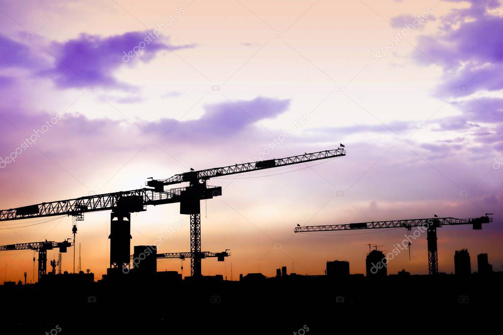 Silhouette crane on top of under construction building at sunset