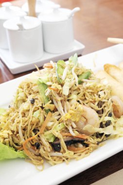 Kızarmış deniz ürünleri erişte beyaz plaka üzerinde