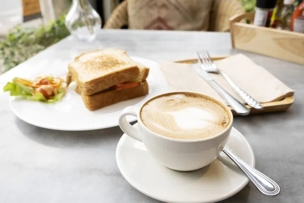 Hot latte coffee and sandwiches on the marble table