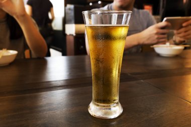 Ahşap bir masa üzerinde uzun bir bardak soğuk bira